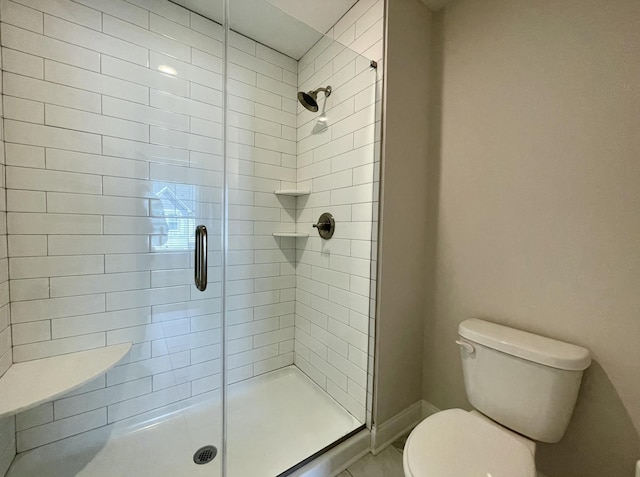 bathroom featuring a stall shower, toilet, and baseboards