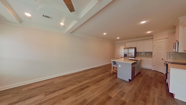 kitchen featuring stainless steel appliances, tasteful backsplash, dark wood-type flooring, white cabinets, and an island with sink