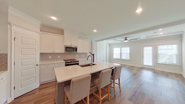 kitchen featuring white cabinetry, a center island with sink, appliances with stainless steel finishes, and light countertops