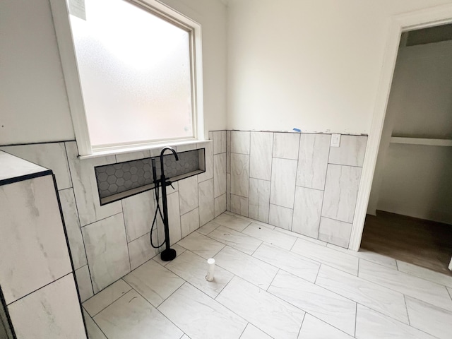 bathroom featuring a wealth of natural light and tile walls