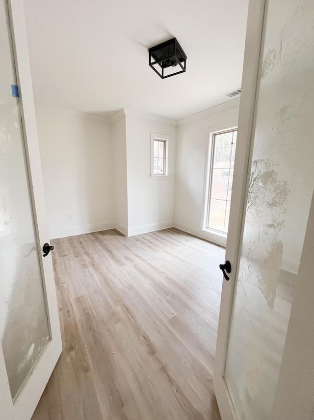 empty room with light hardwood / wood-style flooring and crown molding