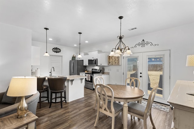 dining area featuring sink, dark hardwood / wood-style floors, french doors, and an inviting chandelier