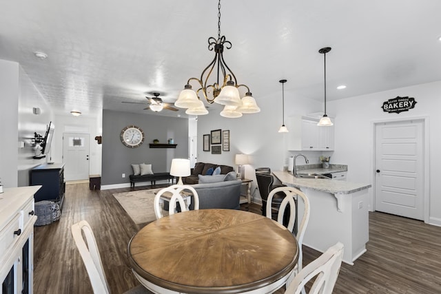 dining area featuring dark hardwood / wood-style flooring, ceiling fan with notable chandelier, and sink