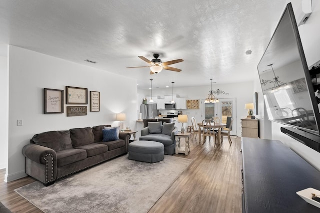 living room featuring hardwood / wood-style flooring, a textured ceiling, ceiling fan, and french doors