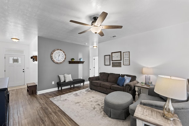 living room with a textured ceiling, ceiling fan, and dark hardwood / wood-style floors