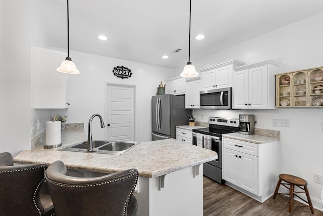 kitchen with a kitchen breakfast bar, stainless steel appliances, pendant lighting, and sink