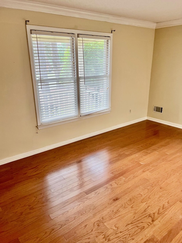 spare room featuring wood finished floors, baseboards, and ornamental molding