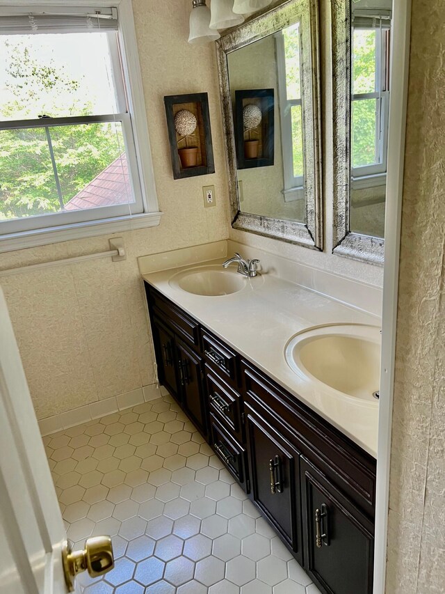 full bath featuring healthy amount of natural light, a textured wall, double vanity, and tile patterned floors