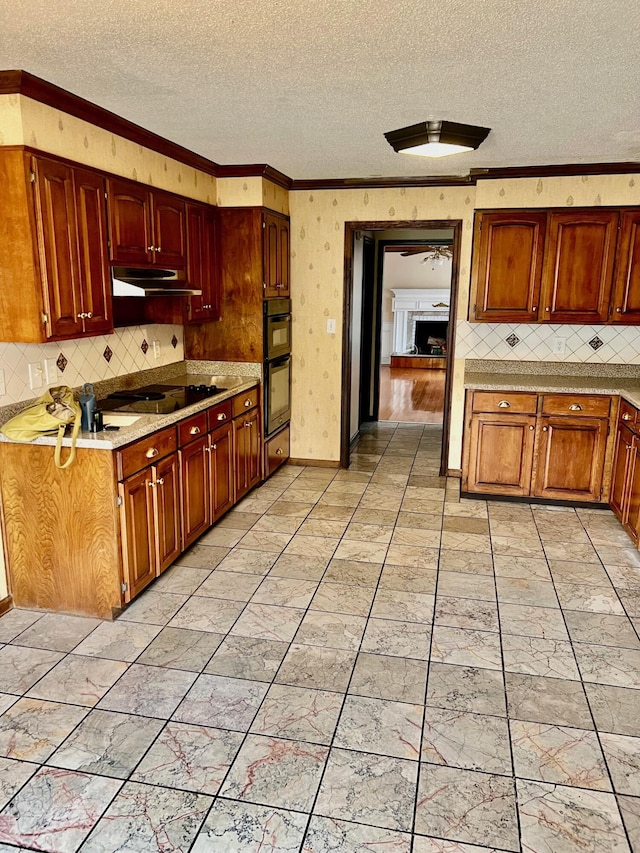 kitchen featuring a textured ceiling, black appliances, under cabinet range hood, crown molding, and light countertops