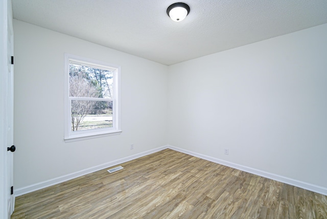 empty room featuring wood-type flooring and a textured ceiling