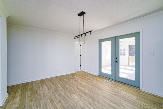 unfurnished room featuring a textured ceiling, ornamental molding, and french doors