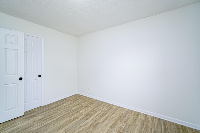 spare room featuring a textured ceiling and light wood-type flooring