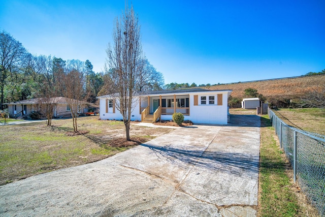 ranch-style home with a front lawn, a porch, and a shed