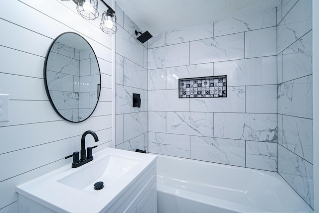 bathroom with tiled shower / bath combo, vanity, and a textured ceiling