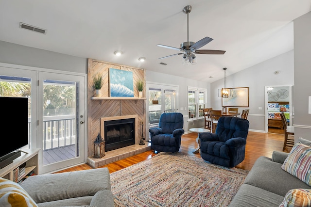 living room featuring ceiling fan, a fireplace, lofted ceiling, and light wood-type flooring