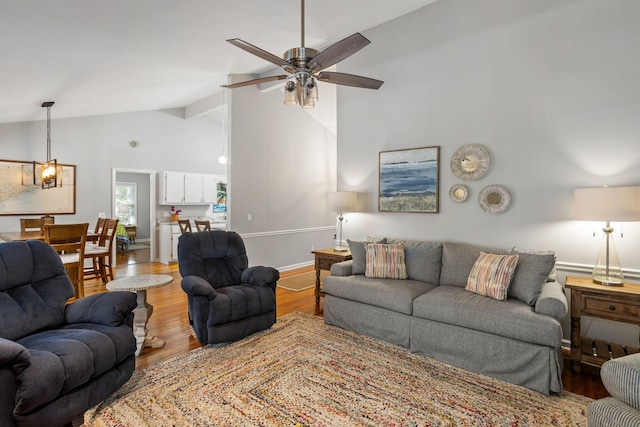 living room featuring ceiling fan, light hardwood / wood-style flooring, and vaulted ceiling