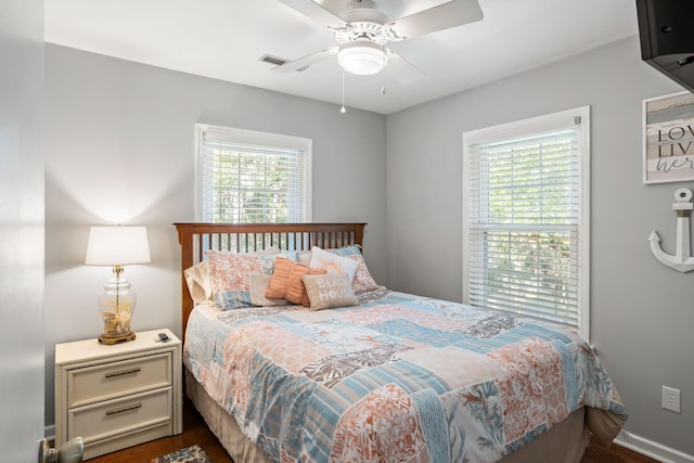 bedroom with ceiling fan, dark hardwood / wood-style flooring, and multiple windows