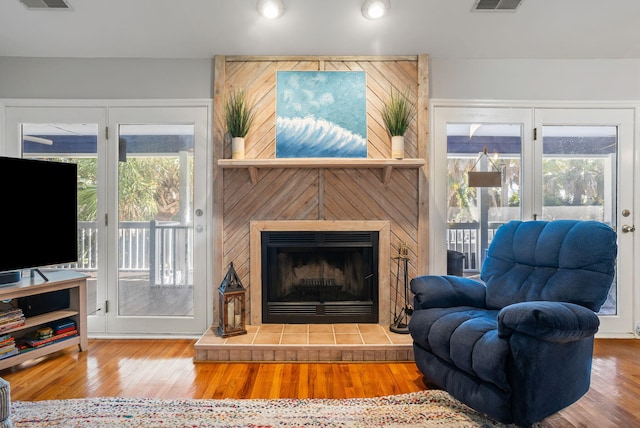 living room with wood-type flooring and a tiled fireplace