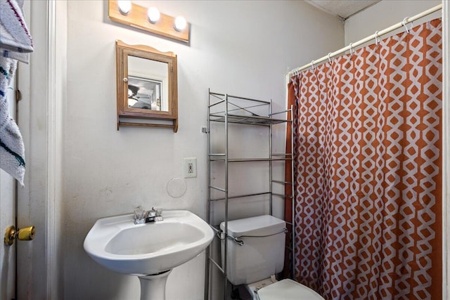 bathroom with walk in shower, sink, and toilet