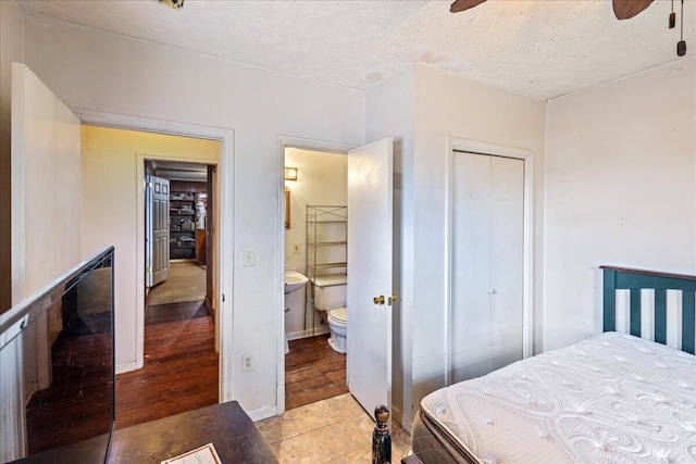 bedroom with light tile patterned floors, ceiling fan, a textured ceiling, ensuite bath, and a closet