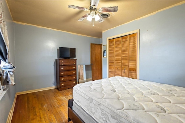 bedroom featuring crown molding, ceiling fan, wood-type flooring, and a closet