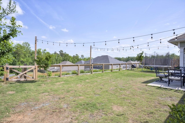 view of yard with a patio, a trampoline, and fence