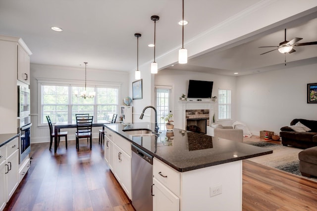 kitchen with stainless steel appliances, dark wood-style flooring, a fireplace, a sink, and open floor plan