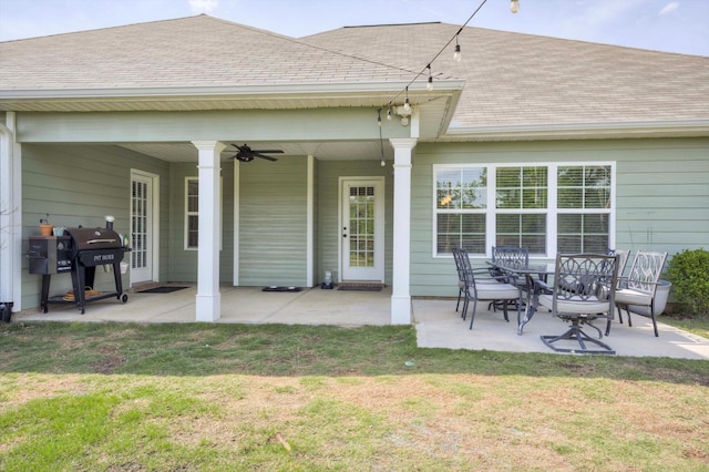rear view of property featuring a lawn, a patio, a ceiling fan, and a shingled roof