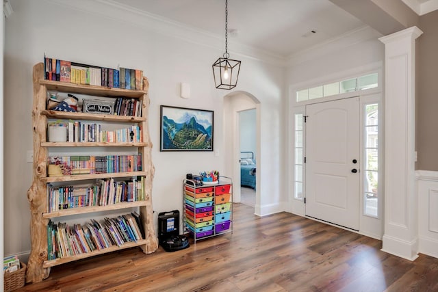 entryway featuring wood finished floors, crown molding, and arched walkways