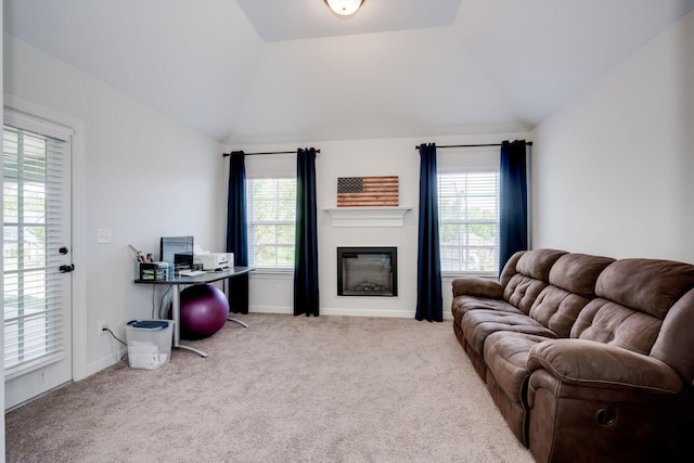 living room featuring a glass covered fireplace, vaulted ceiling, carpet, and baseboards
