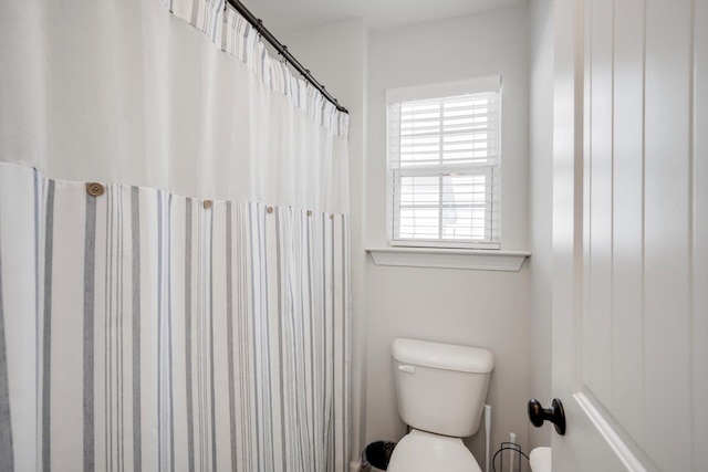 full bath with toilet and a shower with curtain