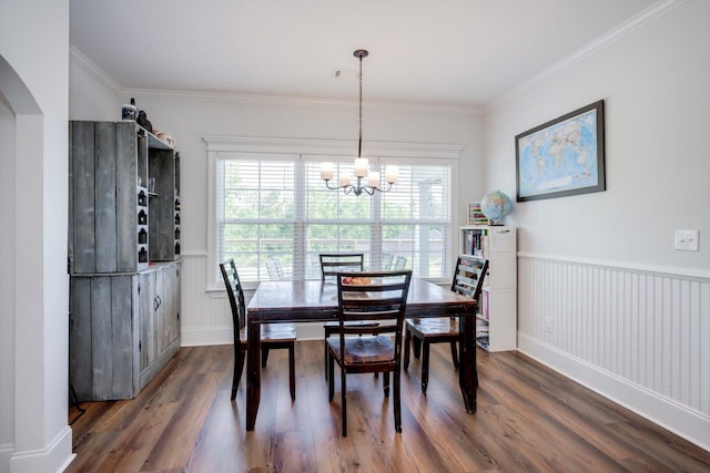dining space with ornamental molding, dark wood-style floors, an inviting chandelier, and wainscoting