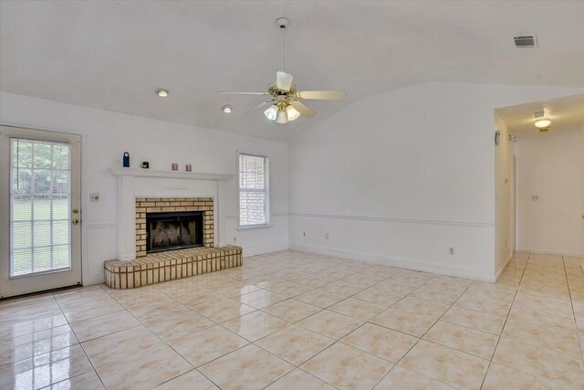 unfurnished living room with ceiling fan, a fireplace, light tile patterned floors, and vaulted ceiling