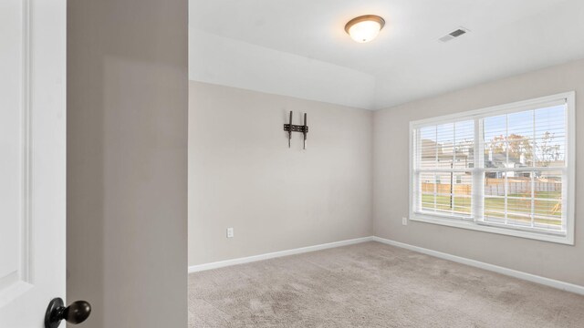 carpeted spare room with lofted ceiling, baseboards, and visible vents