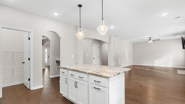 kitchen featuring dark wood finished floors, a ceiling fan, and arched walkways