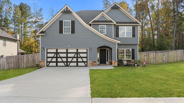 view of front of house featuring a front yard, concrete driveway, fence, and stone siding