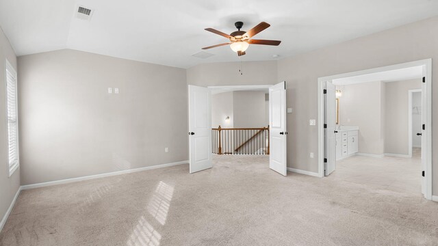 unfurnished bedroom featuring visible vents, lofted ceiling, baseboards, light colored carpet, and ceiling fan