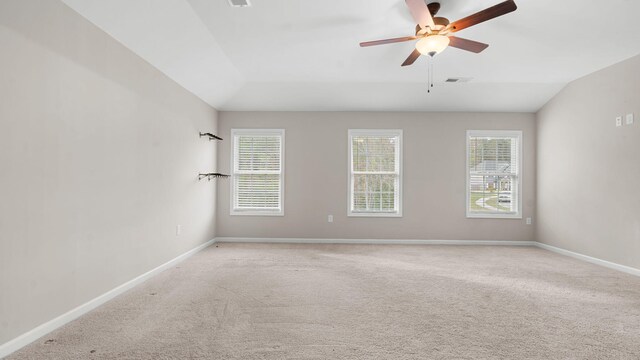 spare room featuring visible vents, lofted ceiling, baseboards, and light carpet