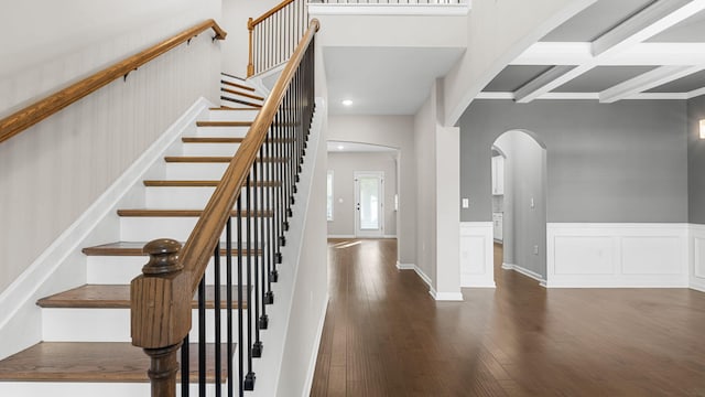 stairs with beamed ceiling, hardwood / wood-style floors, and coffered ceiling