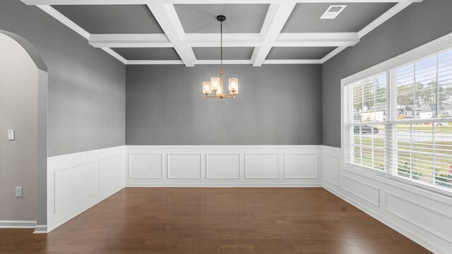 unfurnished dining area featuring arched walkways, a notable chandelier, dark wood finished floors, and beamed ceiling