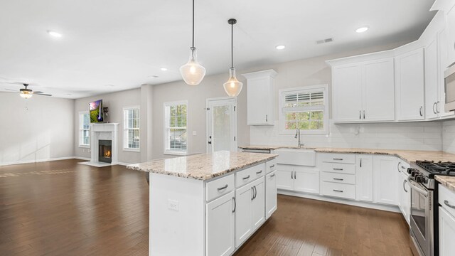 kitchen with dark wood-type flooring, a sink, open floor plan, ceiling fan, and stainless steel gas range