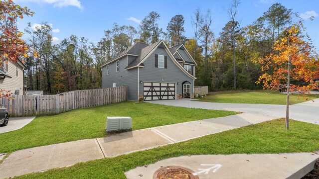 view of property exterior featuring a lawn, driveway, a garage, and fence