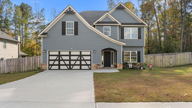 view of front of home featuring a front lawn, fence, stone siding, and driveway