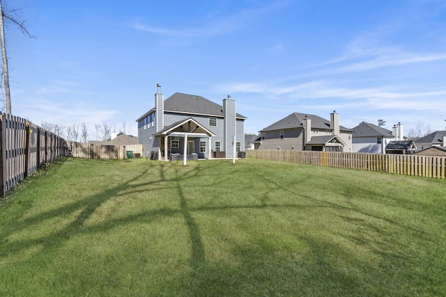 back of house featuring a fenced backyard and a yard