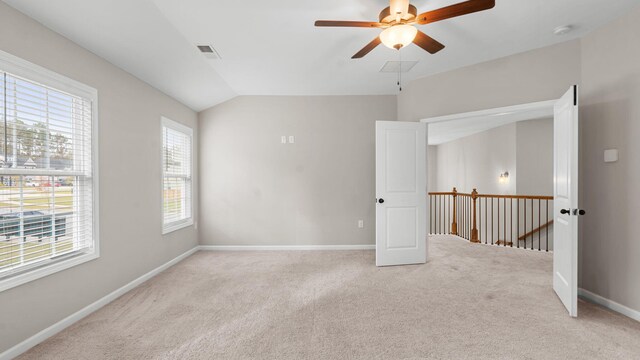 carpeted empty room featuring visible vents, baseboards, ceiling fan, and vaulted ceiling