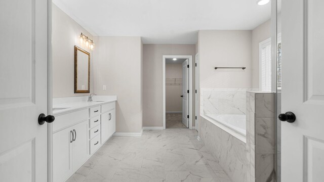 full bathroom featuring a spacious closet, baseboards, a garden tub, marble finish floor, and vanity