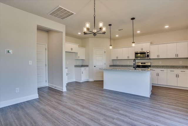 kitchen with appliances with stainless steel finishes, decorative light fixtures, a kitchen island with sink, and white cabinets