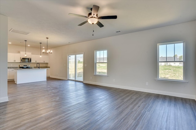 unfurnished living room with ceiling fan with notable chandelier, sink, and hardwood / wood-style floors