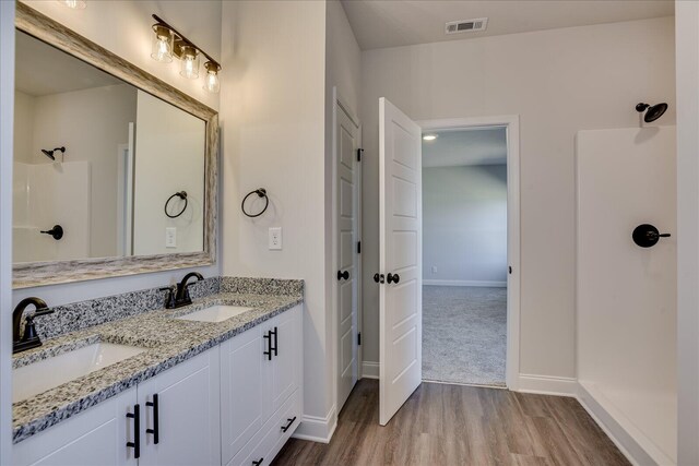 bathroom with hardwood / wood-style flooring, a shower, and vanity