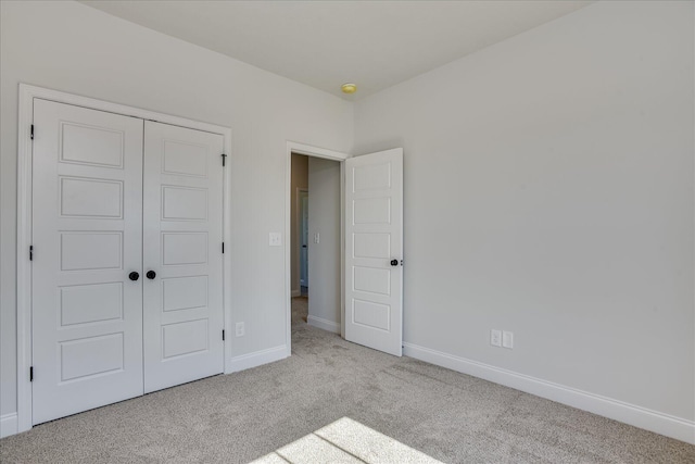 unfurnished bedroom with light carpet and a closet